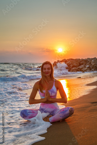 Happy woman with closed eyes sitting in a lotus position on the seashore