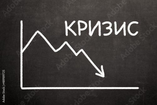 The word crisis in Russian next to a financial graph of a falling stock market. Concept on the financial, economic and political crisis in the world due to the outbreak of the war.