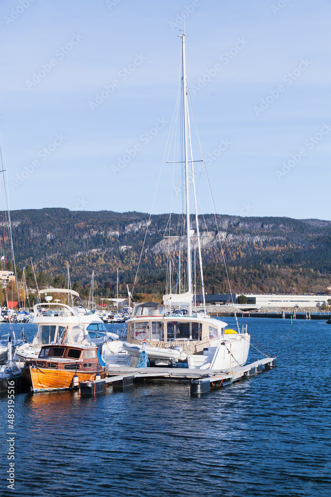 Sailing and motor boats are moored in Norwegian harbor