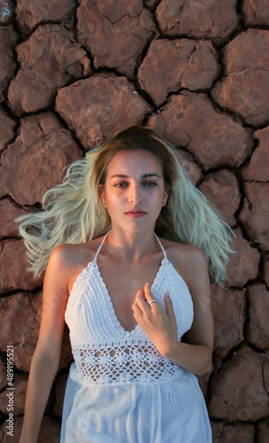 woman in white lying on the cracked desert floor