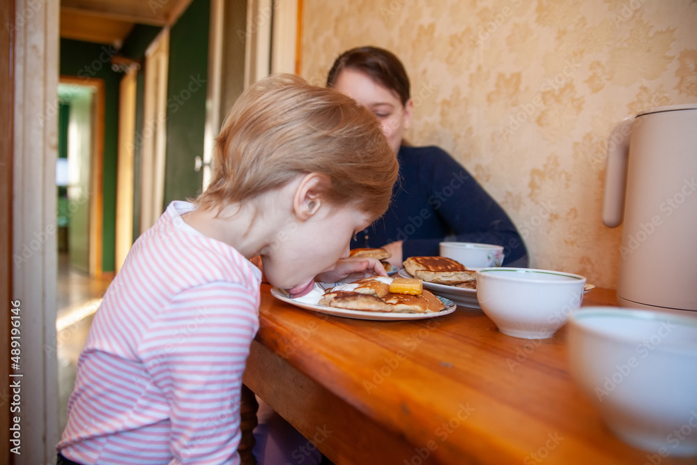 Toddler girl with older sister at   breakfast table eating pancakes.