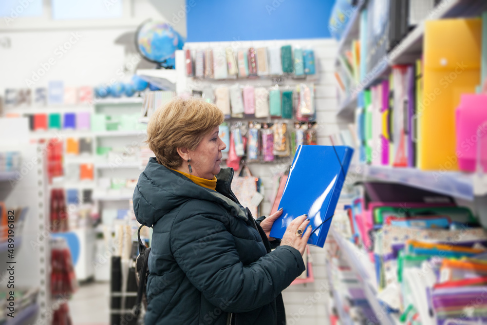  mature woman between   shelves with stationery.