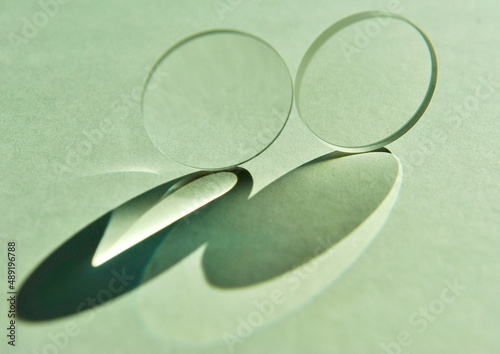 Two circular convex lens with different focus lengths put close together creating refraction image and reflection of shade and shadow on white paper background. Beautiful elliptical shadow pattern photo