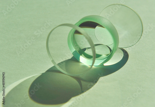 Closeup of sunlight through clear circular convex and concave lens with different focus lengths overlapping. Mixture refection and refraction of light create artistic shade and shadow on white paper photo