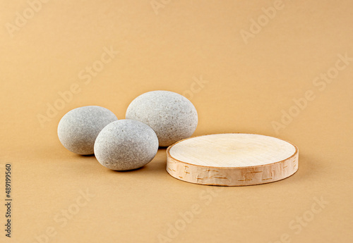 Wooden podium and light stones on a pastel beige background. Minimalism