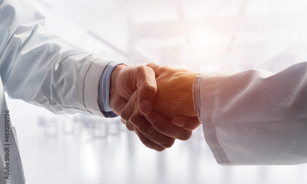 Close-up of the handshake between the two medics. Against the backdrop of the cityscape