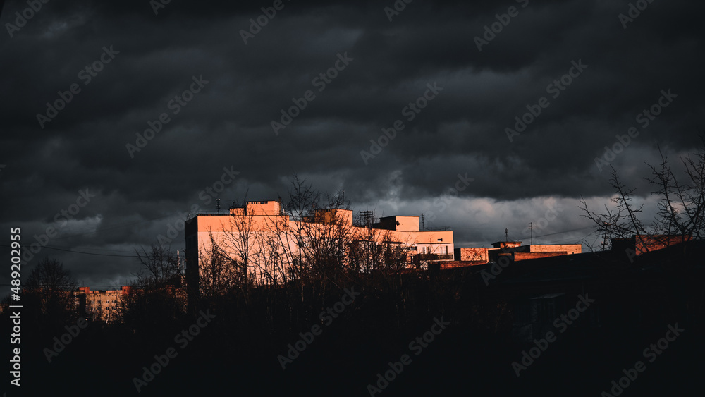 gloomy view of the city of Ukraine. sunset in the city. cloudy sky. thick black clouds. the light of the sun is reflected on the building.