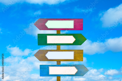 Colorful wooden direction arrow signs on a wooden pole on sky background. 