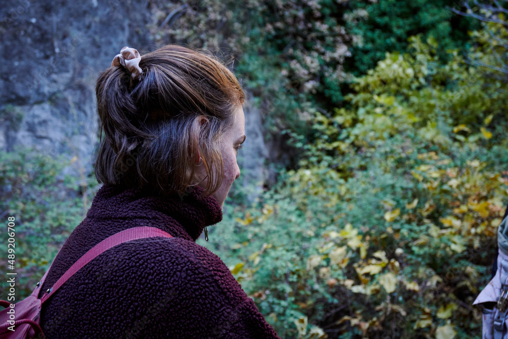 A side view of a short-haired female enjoying a mesmerizing view of nature in the green forest A side view of a short-haired female enjoying a mesmerizing view of nature in the green forest