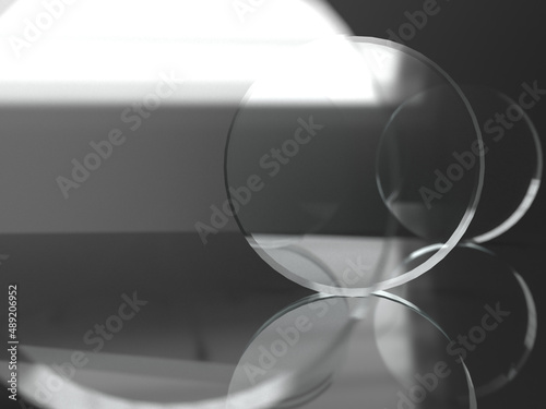 Fototapeta Naklejka Na Ścianę i Meble -  three glass lenses on a reflective surface before black background with focus on second lens. 3D rendering.