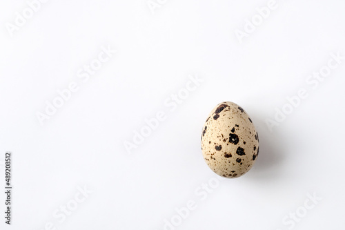 one quail egg on white background. Top view. Home cooking. The idea of healthy breakfast, symbol of Easter. Copy space