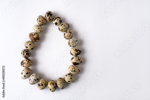 quail eggs are stacked in one large egg on a white background. Top view. Copy space