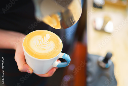 barista pouring milk into espresso coffee for making cappuccino, latte art