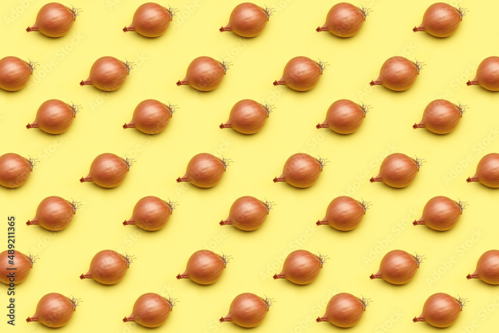 Onion head in a golden yellow peel on a yellow background. Pattern, template, background, studio shot. Onion head in a golden yellow peel on a yellow background. Pattern, template, background, studio shot.