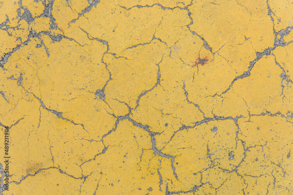 Cracks on yellow paint concrete surface cracked weathered cement worn texture broken abstract damaged pattern background