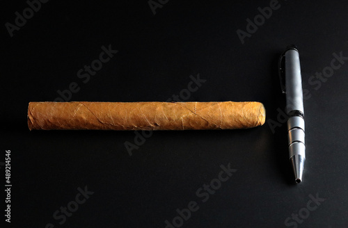 Cuban cigar and pen on black background