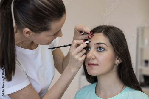 A brunette girl does eyebrow correction and coloring in the salon. Eyebrow care. Close-up.