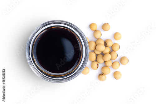 Soy sauce in glass bowl with soybeans isolated on white background. Top view. Flat lay. photo