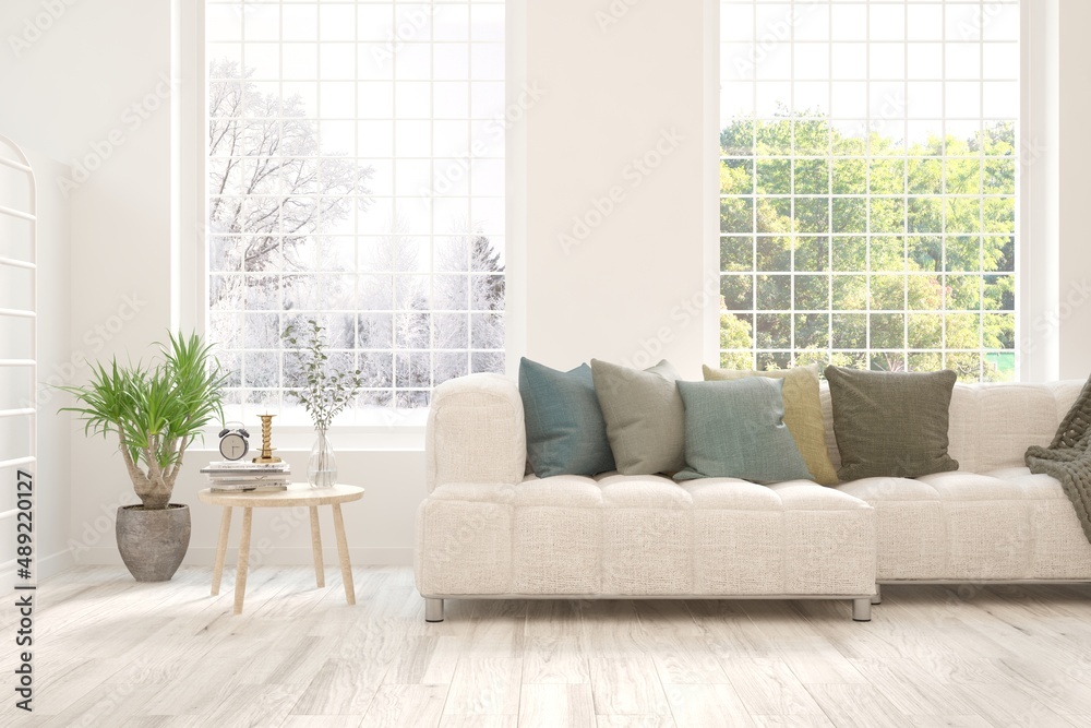 Fototapeta premium White living room with sofa and winter-summer landscape in window. Scandinavian interior design. 3D illustration