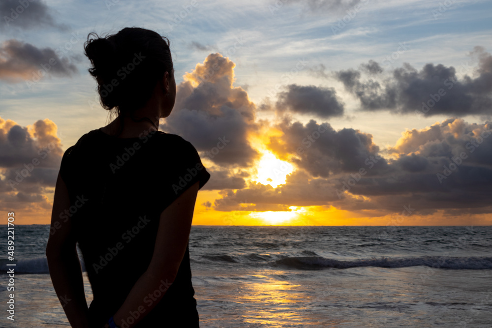 Female silhouette and scenic sunrise above ocean in the background. Woman in nature. Female silhouette and scenic sunrise above ocean in the background. Woman in nature.