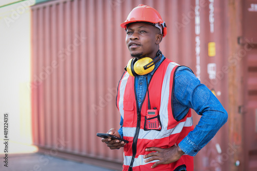 African black male worker standing smiling happily and wearing safety work equipment clothes Work at a warehouse, ship, cargo, import, export industry.