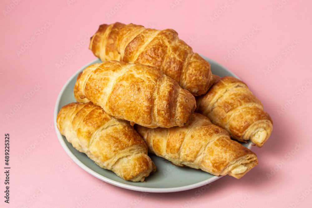 Fresh croissants on a pink background. Tasty breakfast. Traditional pastries.