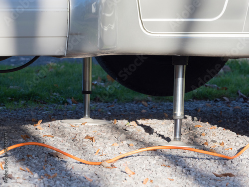 Close view of two hydraulic levelling jacks used to level a motorhome recreational vehicle on a gravel surface.Technology photo
