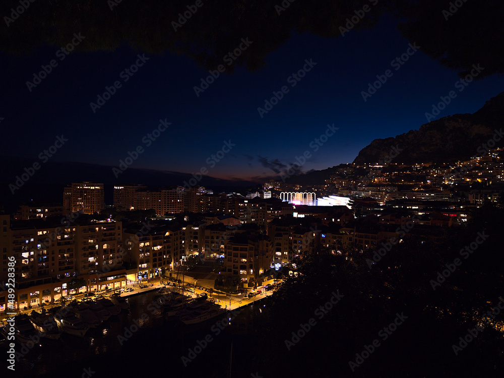 Beautiful night view of marina Port de Fontvieille in Monaco at the French Riviera with modern apartment buildings and illuminated stadium.