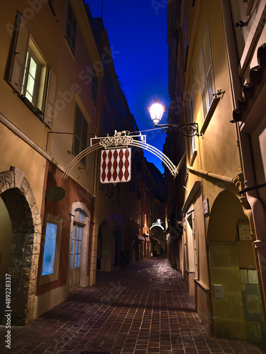 Beautiful night view of empty narrow alley in the historic center of Monaco (Monaco-Ville) at the mediterranean coast with illuminated old building.