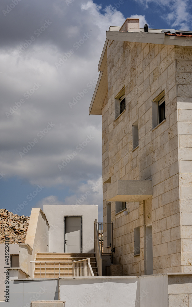 White stone house in the desert against a blue sky with clouds.