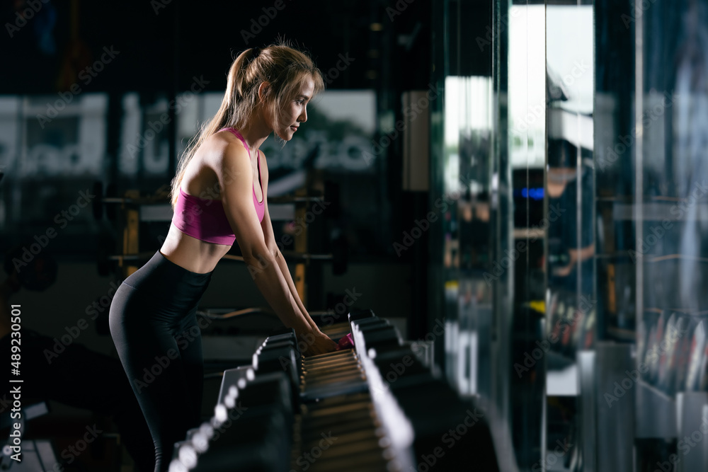 sports sexy women standing are working out with dumbbells in gym and cinematic tone process