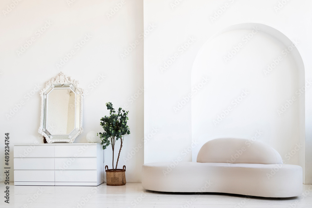 The interior of a modern living room. Minimalistic interior of the apartment. Sofa and chest of drawers with a large mirror on the wooden floor.