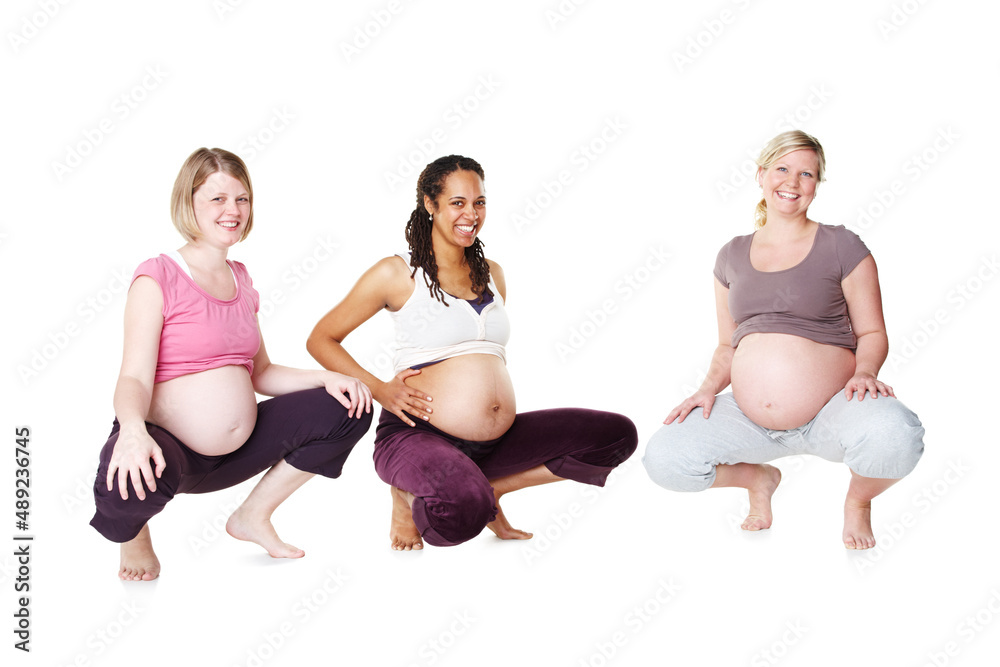 Feeling great about their pregnancies. Three pregnant women crouching and smiling while isolated on a white background.
