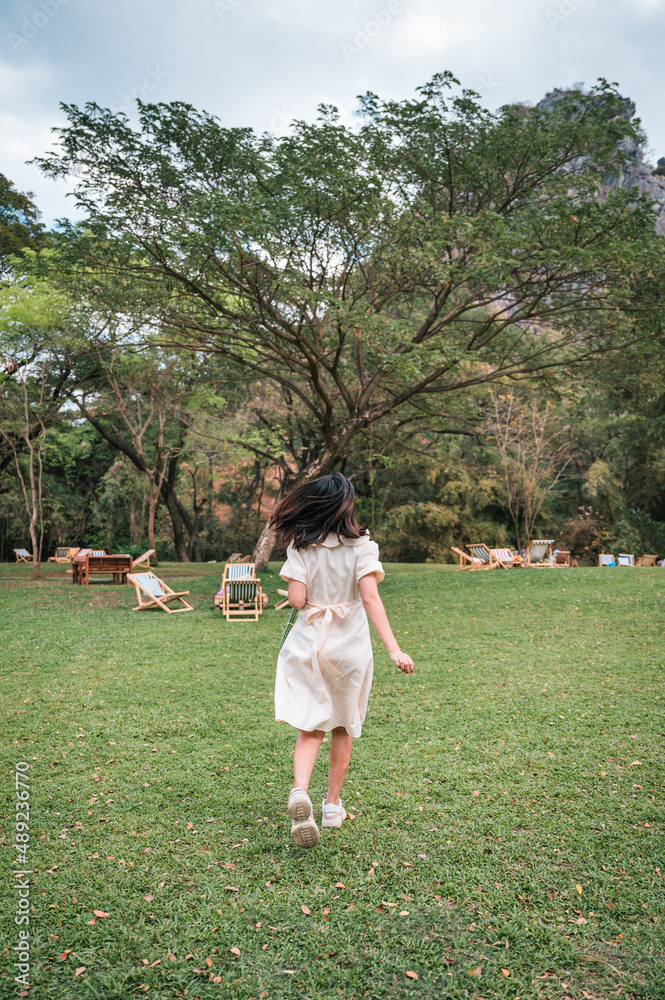 Happy young asian woman in dress running enjoying leisure on lawn in the park Happy young asian woman in dress running enjoying leisure on lawn in the park