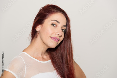red-haired girl, smiling, looking straight ahead, with neutral background