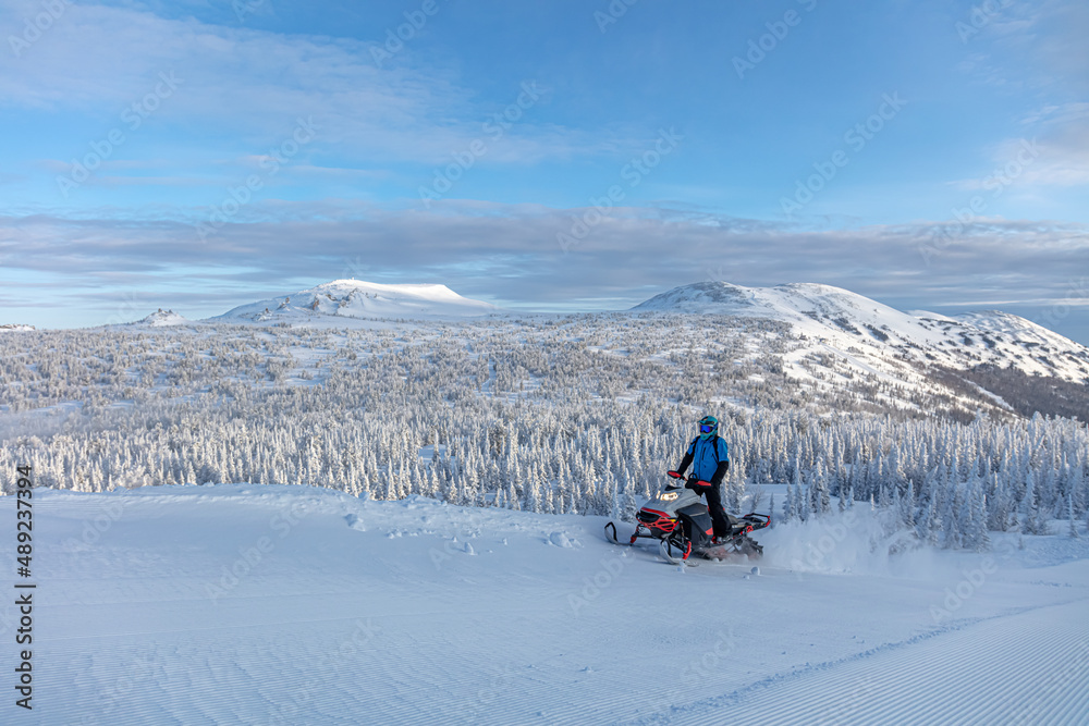 travel on a modern mountain snowmobile against the backdrop of beautiful mountain valleys after a snowfall. Extreme sport adventure, outdoor activity during winter holiday on ski mountain resort