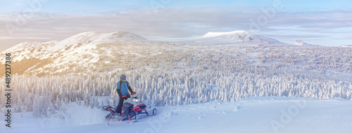 travel on a modern mountain snowmobile against the backdrop of beautiful mountain valleys after a snowfall. Extreme sport adventure, outdoor activity during winter holiday on ski mountain resort
