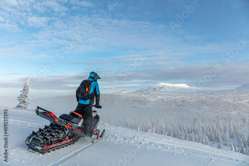 travel on a modern mountain snowmobile against the backdrop of beautiful mountain valleys after a snowfall. Extreme sport adventure, outdoor activity during winter holiday on ski mountain resort