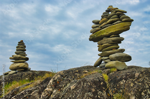 Two cairns made of well-balanced smooth stones on a weathered boulder 