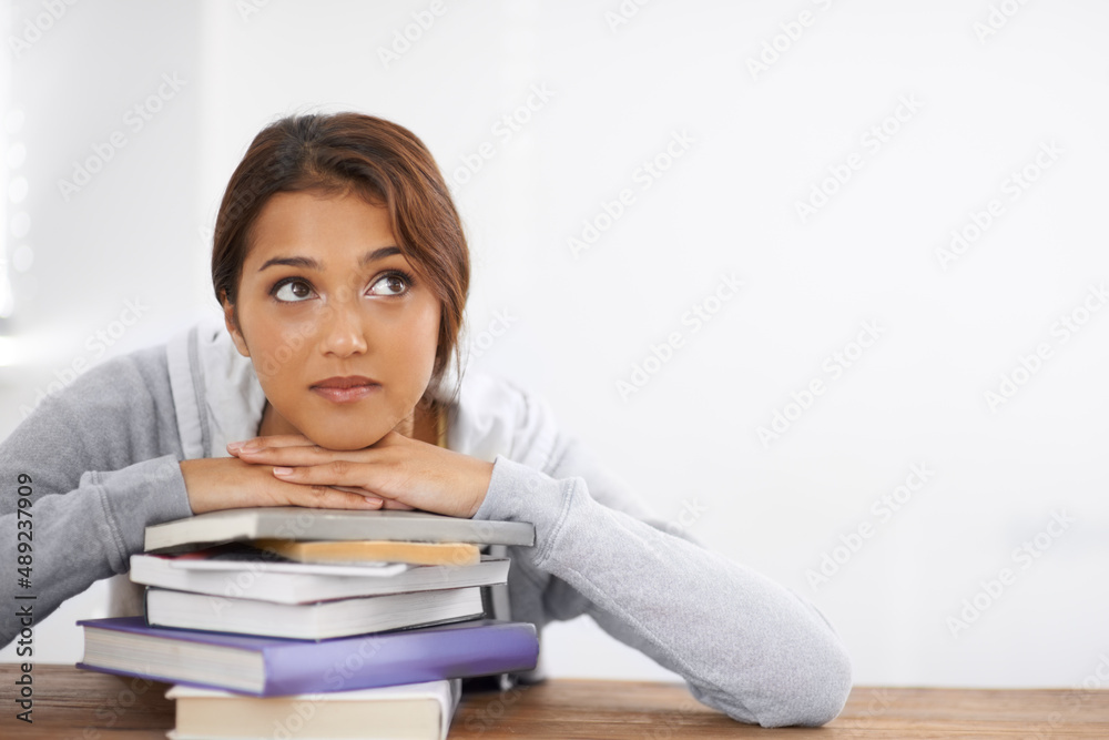 Thinking about solutions to a problem. Closeup shot of an attractive college student leaning on her books and looking thoughtful. Thinking about solutions to a problem. Closeup shot of an attractive college student leaning on her books and looking thoughtful.