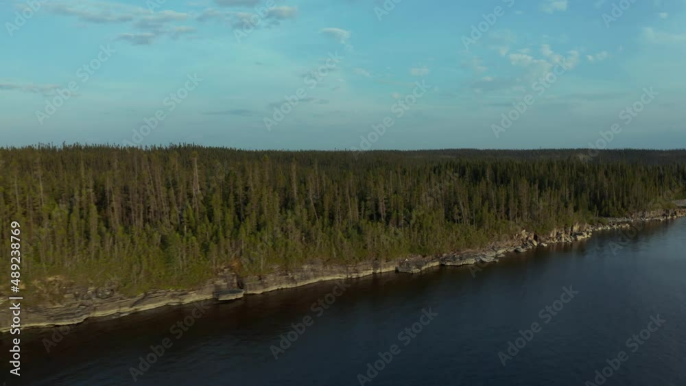 Drone following the shore of a forest with the warm dusk sun Drone following the shore of a forest with the warm dusk sun