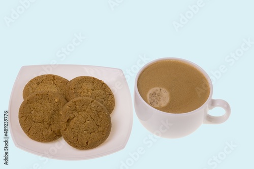View of cup of coffee and oatmeal cookies on saucer isolated on blue background. Food and drink concept.