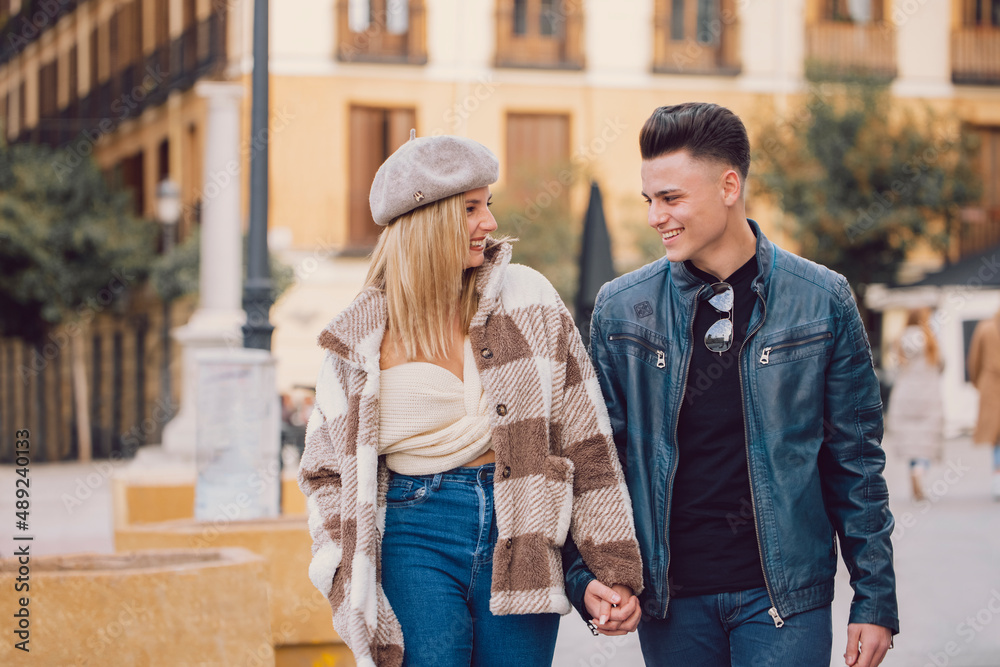 Young couple looks at each other and smiles as they walk through the city of Madrid.