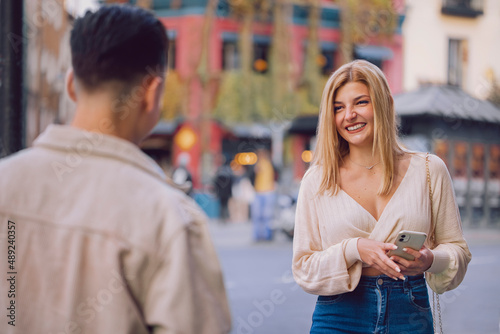 Fényképezés A young girl meets her date in the city while holding her phone.