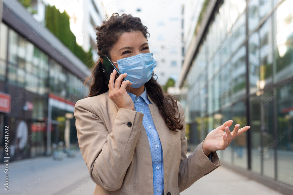 Business woman wearing face mask and talking with somebody on her mobile phone while walking Business woman wearing face mask and talking with somebody on her mobile phone while walking