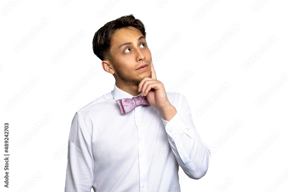 Latin man thinking and looking up wearing pink bow tie and white shirt against a white background Latin man thinking and looking up wearing pink bow tie and white shirt against a white background