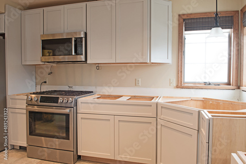 A new kitchen is being installed. Some units and appliances are in place but no countertops and electrical work still needs to be completed.