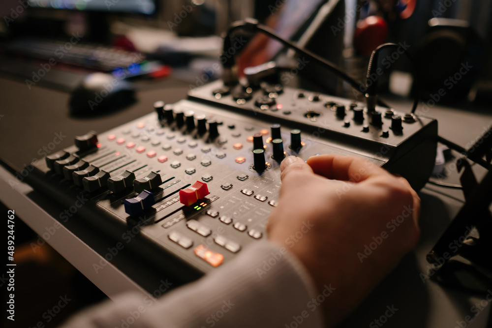 Audio mixer, the young man is touching the knobs of the mixer, close-up mixer, red buttons and slider, professional work console, selective focus Audio mixer, the young man is touching the knobs of the mixer, close-up mixer, red buttons and slider, professional work console, selective focus