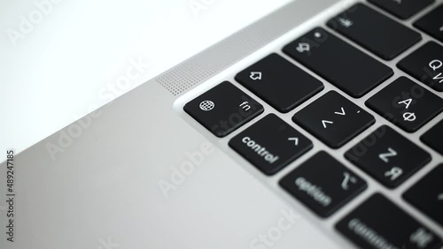 Hand pressing the globe key on modern laptop keyboard close-up slow motion 