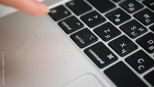 Hand pressing option key on modern laptop keyboard close-up slow motion